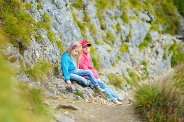 Naklejka na ściany i meble Two sisters enjoying picturesque views from the Tegelberg mountain, a part of Ammergau Alps, located nead Fussen town, Germany.