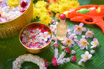 Obraz na płótnie Canvas Thai traditional jasmine garland and Colorful flower in water bowls decorating and scented water, perfume, marly limestone, pipe gun on Banana leaf for Songkran Festival or Thai New Year