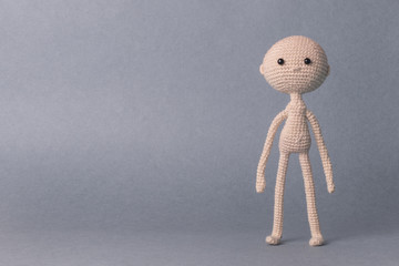 A toy man on a gray background with space for text. Knitted toy amigurumi. Presentation. Motivational phrase. Cute model. Puppet. Sweet doll.