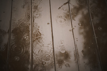 Circles from rain drops on a wooden brown surface in a real garden.