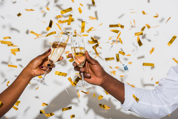 close-up partial view of african american couple clinking glasses of champagne on white with golden...