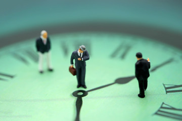 Miniature people : business man looking at watch and walk on the clock background, time business...