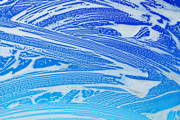 Window cleaning. Glass in soap foam against blue sky background