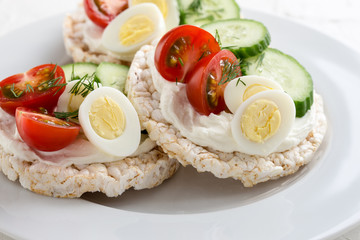 Fototapeta na wymiar Open sandwiches of rice cakes with cream cheese , vegetables and quail egg