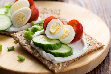 Chia seed crackers with cream cheese, cucumbers, tomato, quail egg and green onion