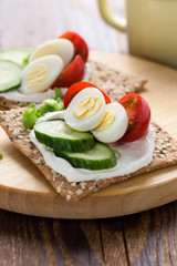Chia seed crackers with cream cheese, cucumbers, tomato, quail egg and green onion