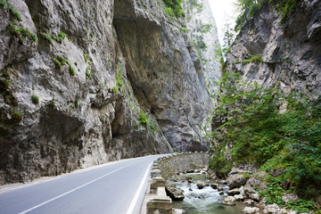 Mountain road in Bicaz Canyon, Romania between high vertical rocky cliffs. One of the most spectacular roads in Romania. Potentially dangerous hairpin curve on a mountain road.