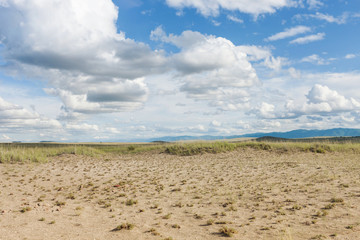 Clouds above the sandy plain near Mongolia. Tyva. Steppe. Sunny summer day. Outdoors