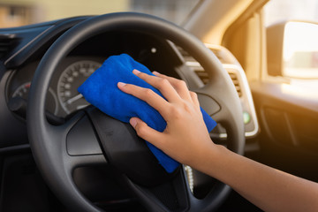 Close-up portrait of woman hand cleaning car steering wheel with microfiber towel