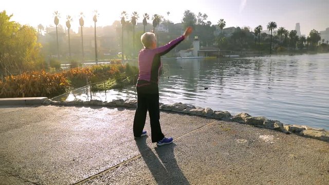 71 year old woman stretching after her morining walk in the park.