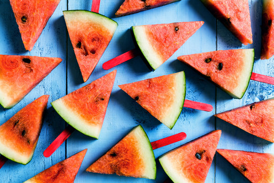 summer concept watermelon slice popsicles on a blue rustic wood background
