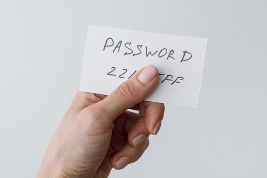 Woman's hand holds a password on paper, that covers the password with finger