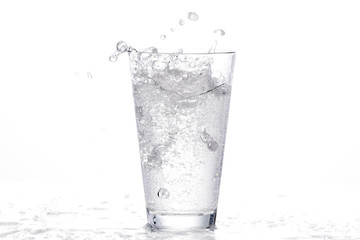 vor weißem Hintergrund: sprudelndes Wasserglas