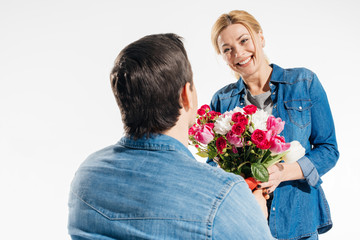 Romantic man giving his girlfriend a bouquet of flowers isolated on white