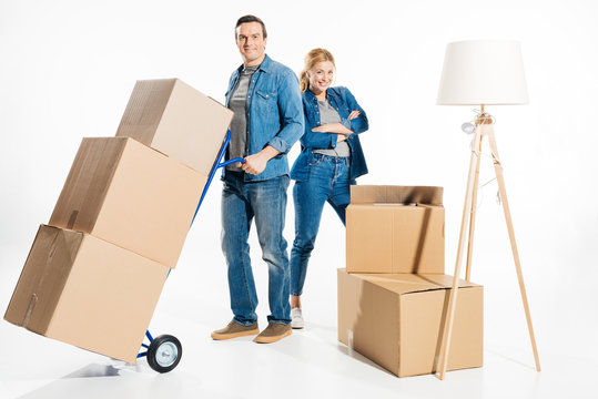 Flat moving concept with woman and man carrying cardboard boxes on delivery cart isolated on white