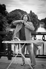 Man ironing his suit in the city, by a canal in Amsterdam