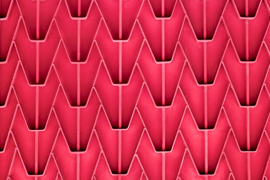 A patterned metal fence with outdated bright red paint. Abstract texture background.