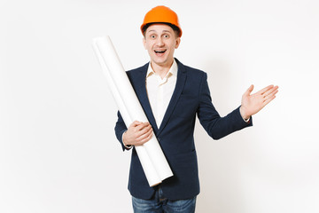 Young happy businessman in dark suit, protective hardhat holding blueprints plans and pointing hand aside on copy space isolated on white background. Male worker for advertisement. Business concept.