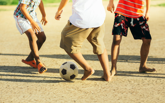 An action and motion picture of an old ball and foot of a kid who is playing football in the sunshine day for exercise.