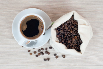 Cup of coffee, coffee beans on the table.