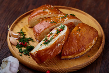 Delicious rustic pastries filled with herbs and vegetables on a wooden plate over a vintage background, selective focus