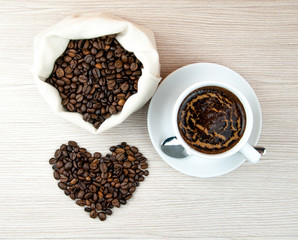 Cup of coffee.Coffee beans heart on the wooden table.