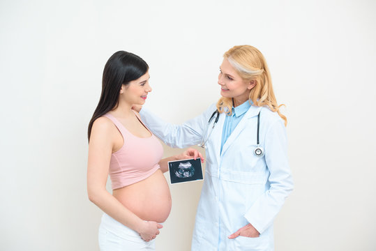 obstetrician gynecologist and young pregnant woman with ultrasound scan picture