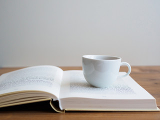 Weiße Tasse auf einem offenen Buch 