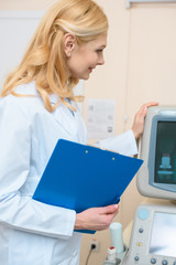 smiling doctor with clipboard touching ultrasonic scanner