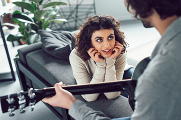 boyfriend playing guitar for attractive girlfriend at home