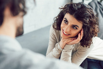 cropped image of smiling girlfriend looking at boyfriend at home