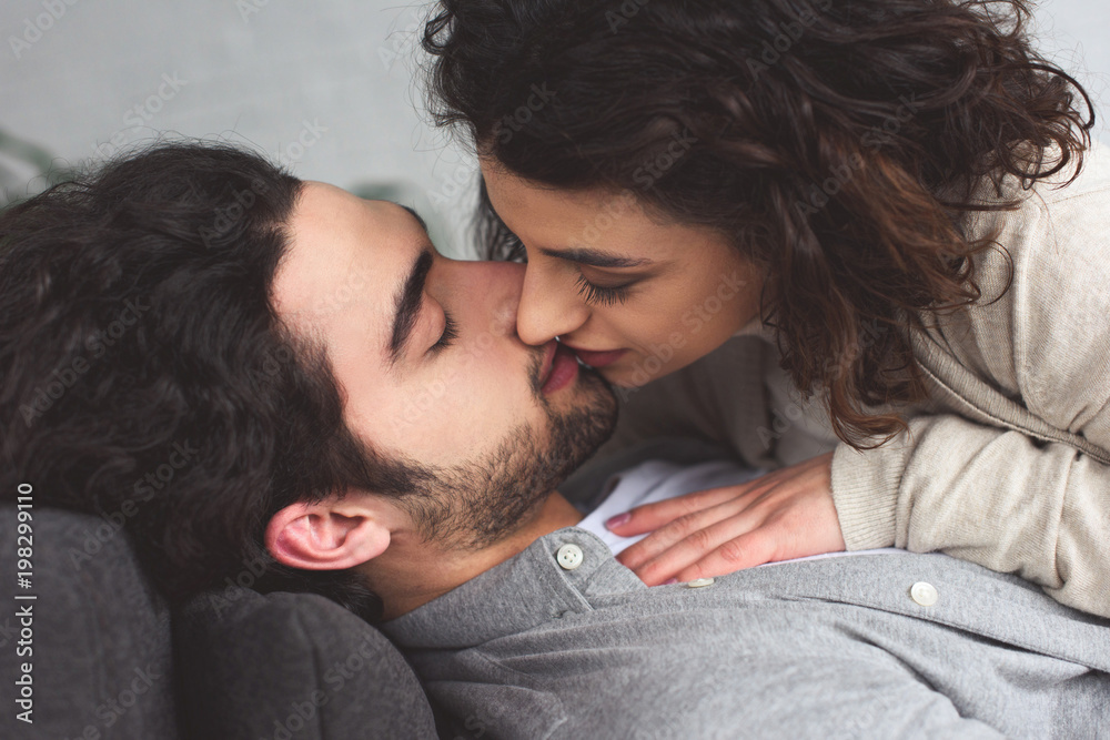 Wall mural young couple lying and kissing at home