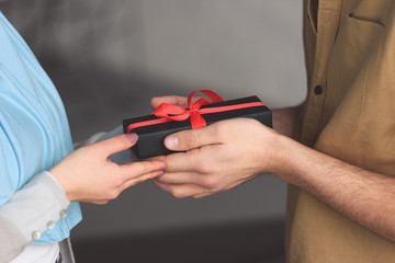 cropped image of muslim boyfriend presenting gift to girlfriend at home