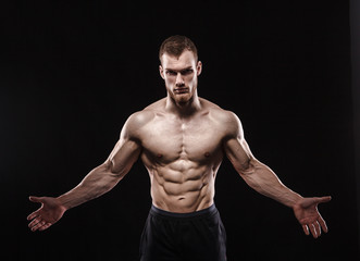 Fototapeta na wymiar Aggressive man is a fighter, a bodybuilder with a naked torso on a black