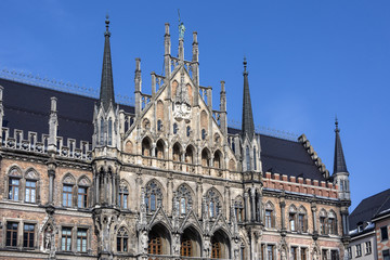 Fototapeta na wymiar Germany, Bavaria, Munich, Marienplatz: Detail of right part of the famous facade of the New Town Hall (Neues Rathaus) in the German city center of the Bavarian capital with blue sky in the background.