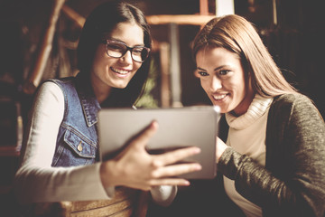 Two young girls sitting at home and using digital tablet.