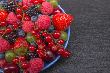 Various summer Fresh berries in a bowl on rustic wooden table. Antioxidants, detox diet, organic fruits.