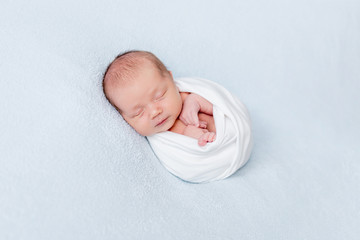Newborn baby sleeping swaddled in blanket
