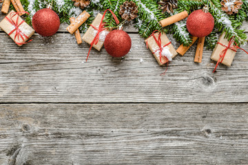 Fir branches with decorations - gift boxes, snow and red ornaments. Christmas background, top view, copy space
