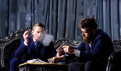 Friends sit with money, alcohol and cigarette.