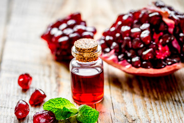 sliced pomegranate and extract in glass on wooden background