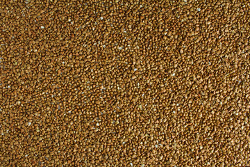 Buckwheat is evenly scattered on a white table.