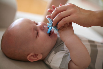 Little baby boy crying and her mother giving pacifier. Close up.