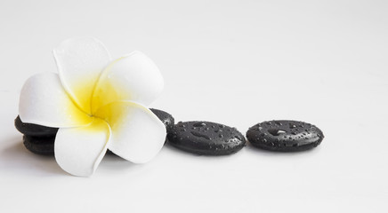 Spa still life with frangipani flower and massage stones isolated on white