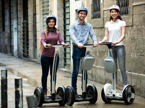 Girls And Guy Traveling Through City By Segways