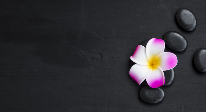 Spa still life with frangipani and massage stones top view, wellness background