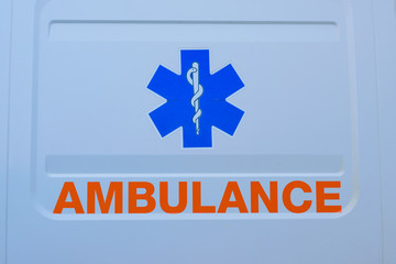 Photograph of ambulance car sign and text on white. The emergency services "Star of Life"