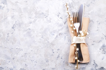 Easter table setting composition: fork, knife silverware wildflowers, pussy willow on plate w/ napkin, white stucco plaster texture background. Close up, top view, copy space
