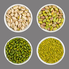 Pistachios in white porcelain bowls. Roasted pistachio seeds in shells and shelled. Green dried fruits, whole and chopped. Pistacia vera. Isolated food photo close up from above on gray background.