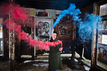 Young girl with blue and red colored smoke bomb in hands.